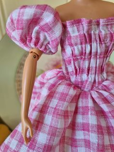 the doll is wearing a pink and white checkered dress