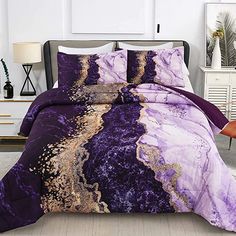 a purple and gold comforter set with pillows