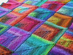 a multicolored crocheted blanket is laying on the floor