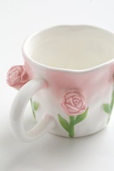 a coffee cup with pink roses painted on the outside and inside, sitting on a white surface