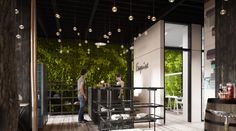 two people are standing at the bar in an open room with plants on the wall