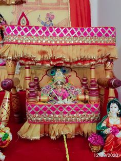 an elaborately decorated bed is displayed in front of a red carpeted area with other decorations