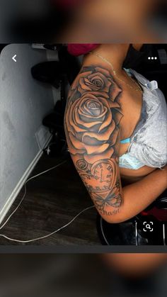 a woman with a clock and rose tattoo on her arm is sitting in a chair