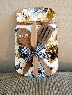 a jar with wooden utensils and spoons in it on a couch next to a wall