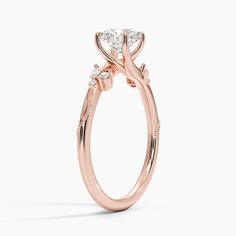 a rose gold engagement ring with three stones on the side and an oval shaped center stone