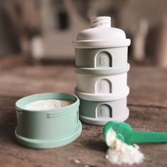 a white and green container sitting on top of a wooden table next to a spoon