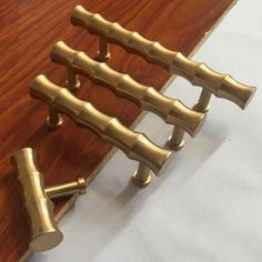 four brass handles on a wooden table with white paper in the backgroung