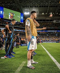 a man standing on top of a soccer field next to another man in a yellow shirt