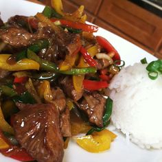 a white plate topped with meat and veggies next to rice