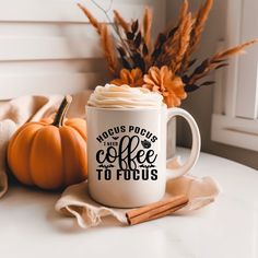 a coffee mug sitting on top of a table next to a pumpkin and some cinnamon sticks