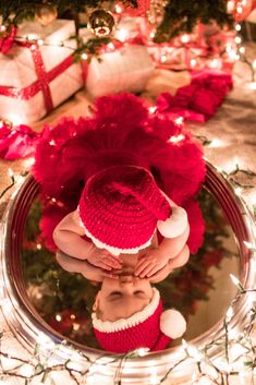 a baby wearing a red hat and diaper is looking at its reflection in a mirror