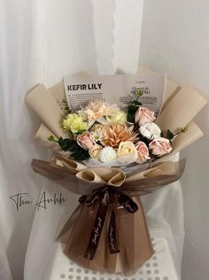 a bouquet of flowers sitting on top of a white chair with ribbon around the neck