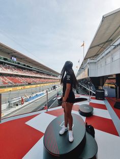 a woman standing on top of a podium in front of an empty race track with red and white checkered flooring