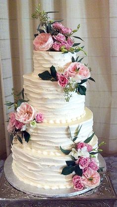 a white wedding cake with pink flowers and greenery