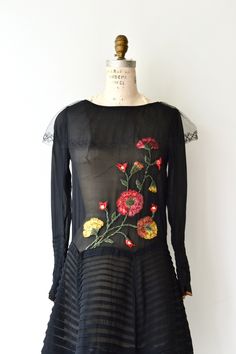 "Antique 1920s sheer black silk dress with scoop neckline, tulle trim, long sleeves with snap cuffs, enchanting crewelwork flowers on the bodice, classic drop waist and horizontal pleated skirt. This dress is in excellent condition, but as with all dresses of this era, should be worn with care as they are approaching 100 years old. [m e a s u r e m e n t s] Fits like: xs/small Bust: up to 34\" Waist: up to 33\" Hip: up to 42\" Length: 40\" Wrist circumference: 5 3/4\" [i n f o] Era: 1920s Brand/ Vintage Spring Evening Flapper Dress, 1920s Style Spring Evening Flapper Dress, 1920s Style Spring Evening Dresses, Vintage Splendor, 1920s Dress Vintage, Vintage 20s Dresses, 20s Dress, Black Silk Dress, 1920s Dress