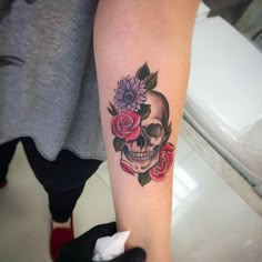 a person with a skull and roses tattoo on their arm