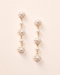 two pairs of earrings with pearls hanging from the side on a white surface, one is gold and the other is silver