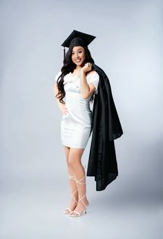 a woman in a graduation gown and cap posing for the camera with her hand on her hip