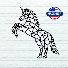 a paper cut unicorn standing on its hind legs in front of a white brick wall