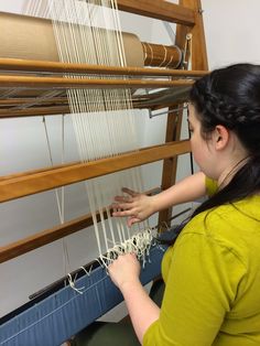 a woman is working on a weaving machine