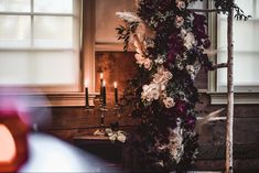 an arrangement of flowers and candles in front of a window