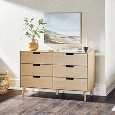 an empty room with a wooden dresser and potted plant