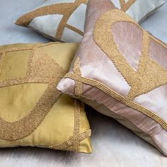 two pillows sitting on top of a bed covered in yellow and brown linens next to each other