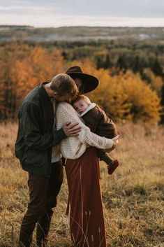 a man and woman hug each other while standing in a field