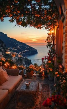 an outdoor seating area with flowers and candles on the patio overlooking the ocean at sunset