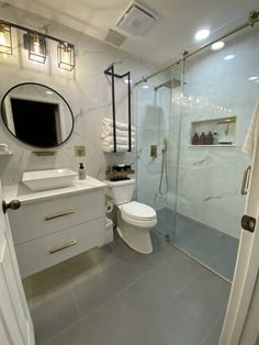 a bathroom with a white toilet sitting next to a walk in shower under a mirror