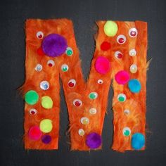 the letter m is made out of orange paper with pom - poms on it