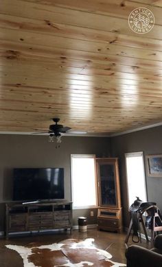 a living room filled with furniture and a flat screen tv on top of a wooden ceiling