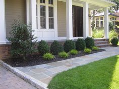 a house with stone walkway leading to the front door and landscaping area in front of it