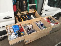 an open drawer in the back of a van filled with assorted items and supplies