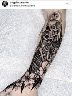 a person with a tattoo on their arm that has a skull and flowers on it