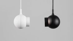 two black and white lamps hanging from the ceiling, one is turned on by a cord