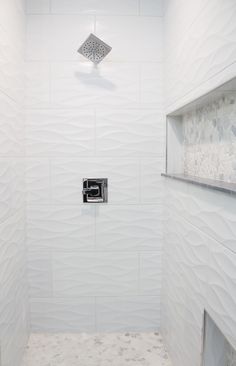 a bathroom with white walls and floor tiles on the shower wall, toilet paper dispenser in the corner