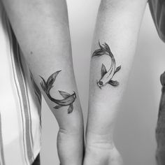 two people holding hands with tattoos on their arms and one has a goldfish tattoo