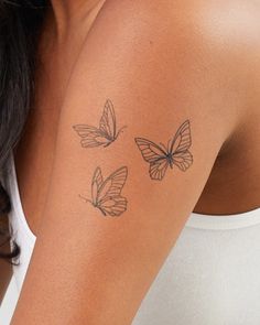 a woman's arm with three butterflies tattooed on the upper half of her arm