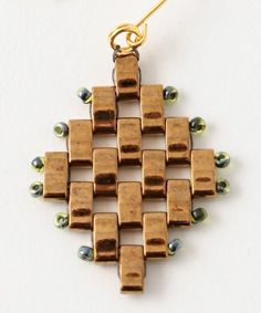 a gold necklace with green beads hanging from it's side on a white surface