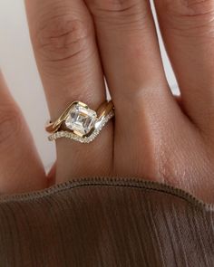 a woman's hand with a diamond ring on top of her finger and an engagement band