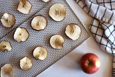 an apple and some cut up apples on a cooling rack next to a plaid towel