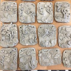 twelve ceramic plaques with animals and fish on them, all in different shapes and sizes