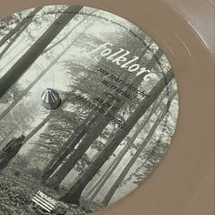 a record that is sitting in the middle of a forest with trees and leaves on it