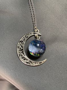 The Grogerous galaxy which hand poured with high quality UV resin.  The necklace come with a moon chain and a sparkling galaxy.  The scene may be changed depending on the light, and your angle of view.  You may choose black or blue galaxy if you like. The pendant is around 4cm across (the galaxy ball is 2cm) and comes on 44cm rhodium plating silver chain.  This material is more shining, sparkling and longlasting than the sterling silver. We use the materials from Japan and South Korea.  Packagin Space-themed Black Jewelry Gift, Magical Silver Resin Jewelry, Silver Resin Jewelry With Magical Style, Adjustable Celestial Necklace For Party, Adjustable Celestial Style Party Necklaces, Silver Resin Necklaces For Parties, Moon Chain, Galaxy Jewelry, Galaxy Necklace