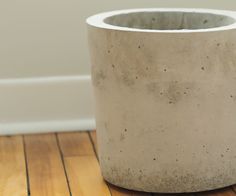 a cement pot sitting on top of a wooden floor