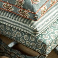 four pillows stacked on top of each other in different colors and patterns, all with decorative designs