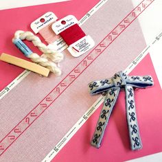 sewing supplies laid out on top of a pink piece of paper with scissors and thread