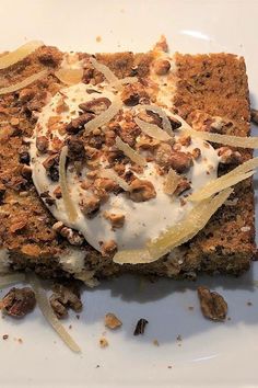 a piece of cake on a white plate with nuts and icing around the edges