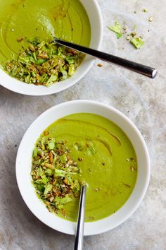 two bowls filled with green soup on top of a table